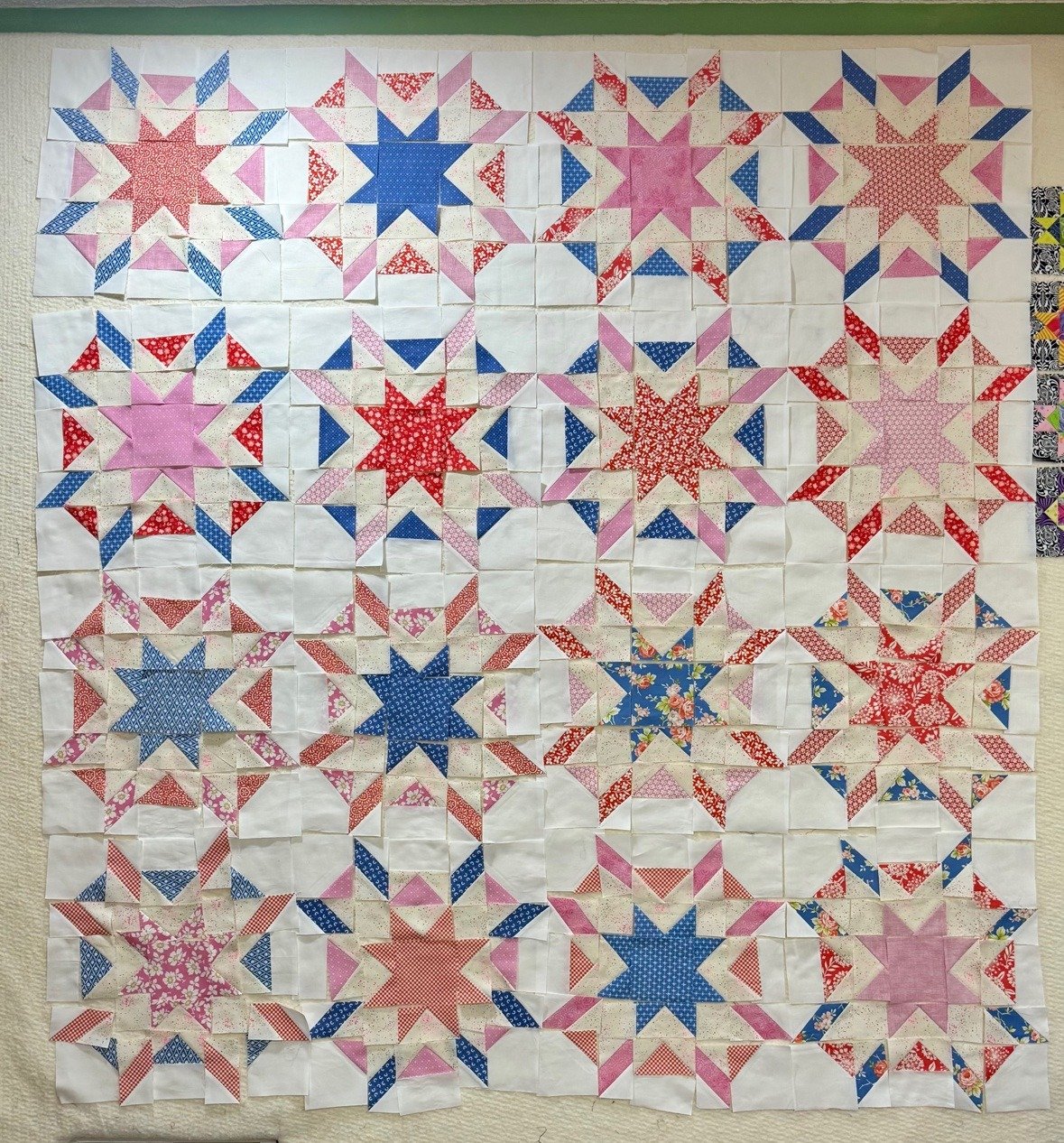 Starfish pieces laid out on the design wall in a four-by-four layout, not sewn together yet